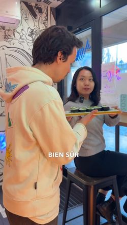 Personne tenant un plateau de sushis à l'intérieur d'un restaurant japonais Rollroll Sèvres.