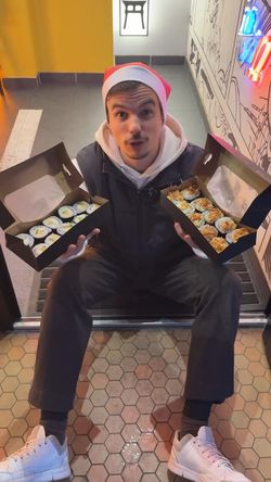 Deux boîtes de sushis avec makis et california rolls, présentées devant l'entrée du restaurant ROLLROLL.