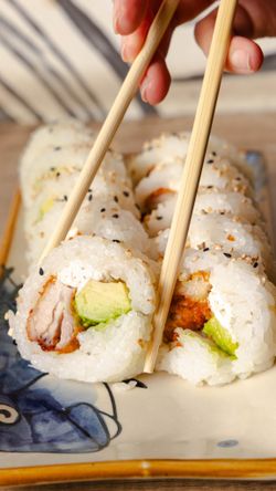 Rouleaux de california rolls garnis d'avocat, fromage frais et poulet pané, servis sur un plat décoratif. Sushi japonais.