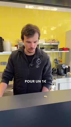 Homme en uniforme ROLLROLL derrière le comptoir dans un restaurant japonais avec carrelage jaune en arrière-plan.