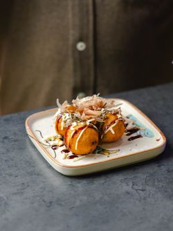 Des boulettes de takoyaki savamment garnies, servies sur une assiette décorée.