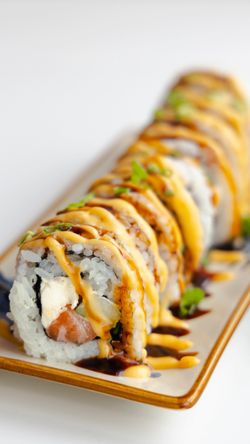 Rouleaux de sushi garnis de saumon, sauce mayonnaise épicée et accompagnés de légumes frais.