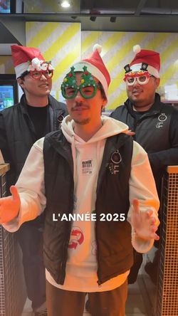 Trois personnes portant des chapeaux de Noël et des lunettes festives devant le comptoir d'un restaurant.