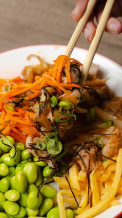 Plat asiatique servi avec edamame, carottes râpées, lamelles de poulet, et garniture de légumes frais au restaurant RollRoll.