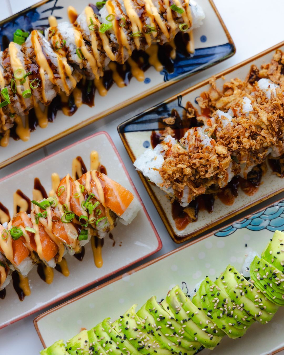 Assortiment de sushis et makis avec du saumon, de l'avocat et des sauces, présenté sur des assiettes.