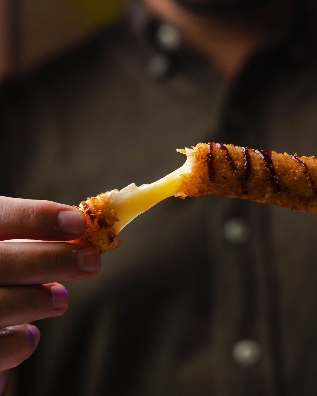 Bâtonnet croustillant au fromage, préparé avec une panure dorée et servie avec une sauce.