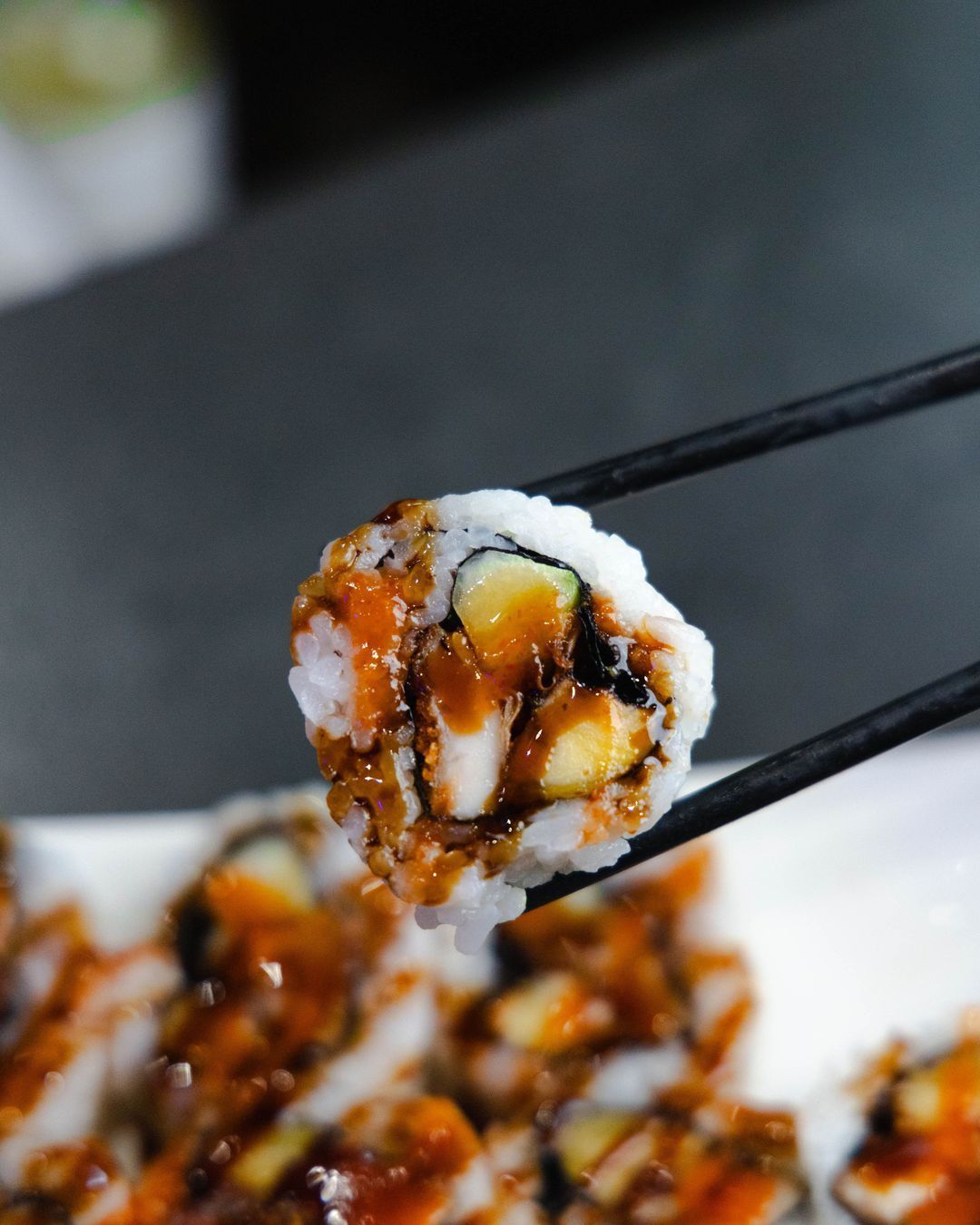 Sushi savoureux avec garniture variée, pris entre des baguettes, typique des restaurants japonais.