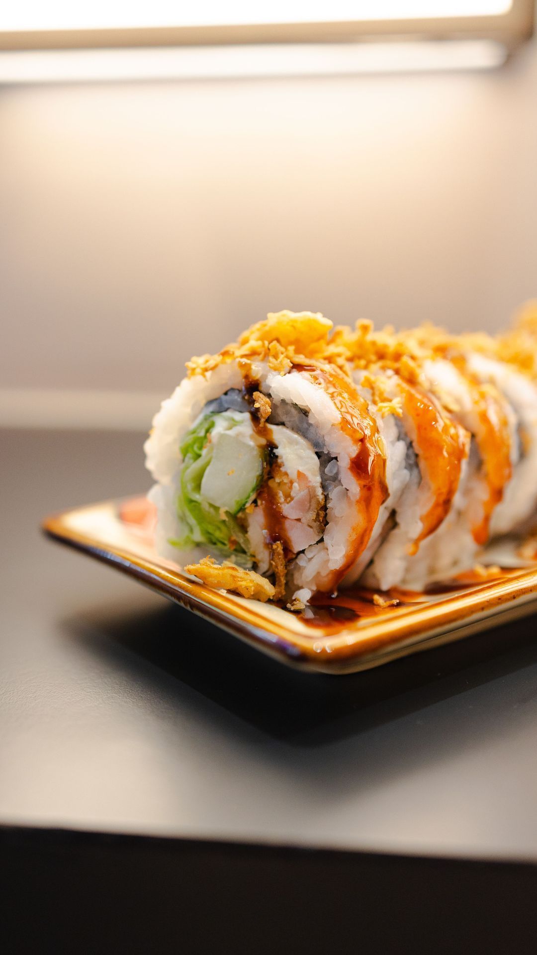 Sushi californien garni, présenté sur une assiette, avec sauce et décor croquant.