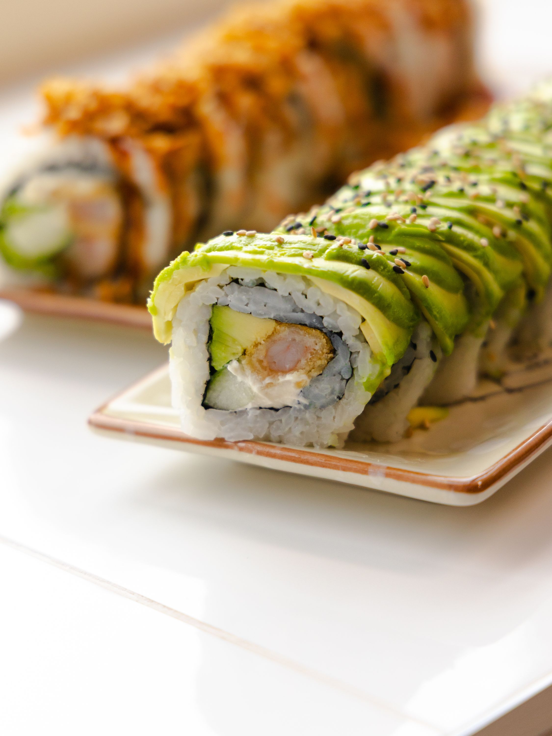 Sushi de type california rolls avec avocat et garnitures sur assiette. Restaurant japonais ROLLROLL Sèvres.