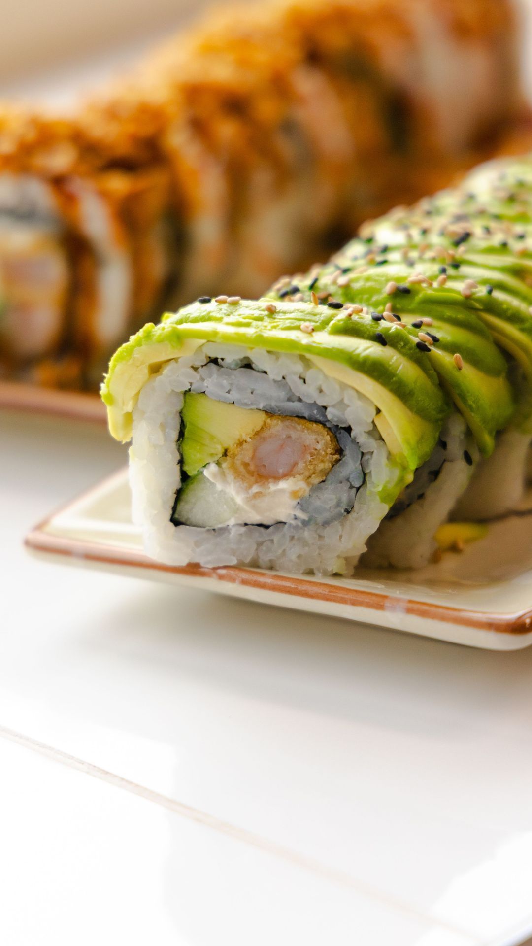 Sushi avec avocat et crevette, servi sur une assiette. ROLLROLL Sèvres propose des plats japonais.