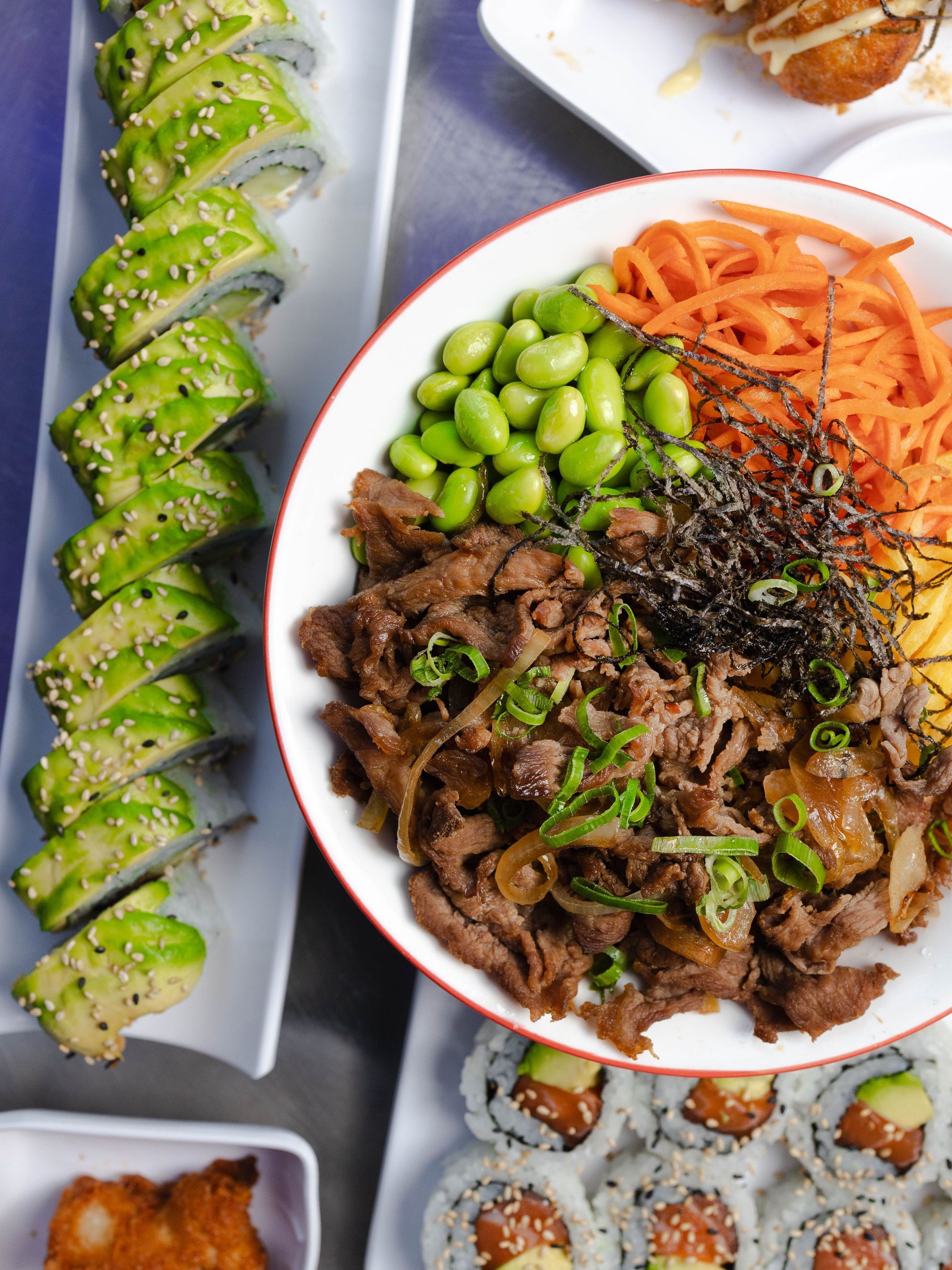 Plat japonais avec rouleaux de sushi à l'avocat et bol de viande, edamame et légumes au restaurant ROLLROLL Vanves