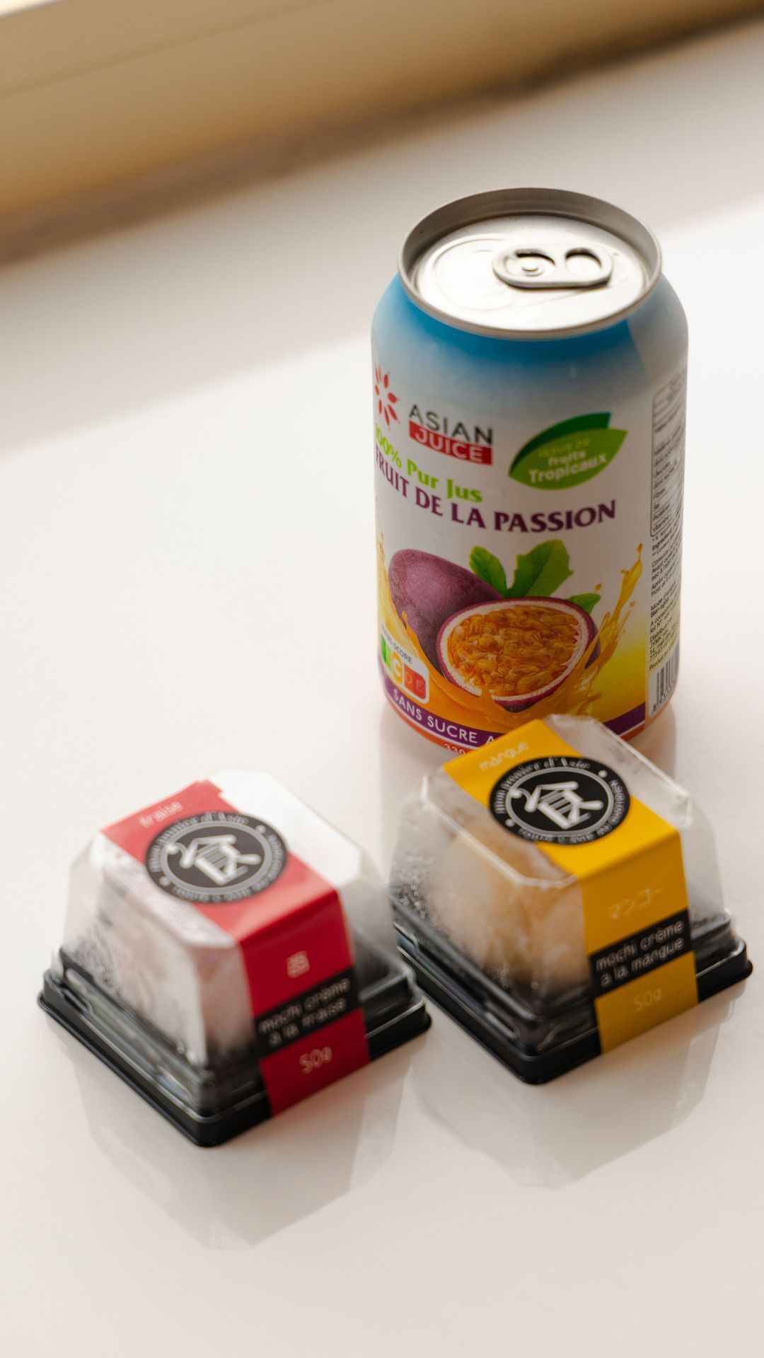 Dessert japonais avec deux petites boîtes de mochi et une canette de jus de fruit de la passion.
