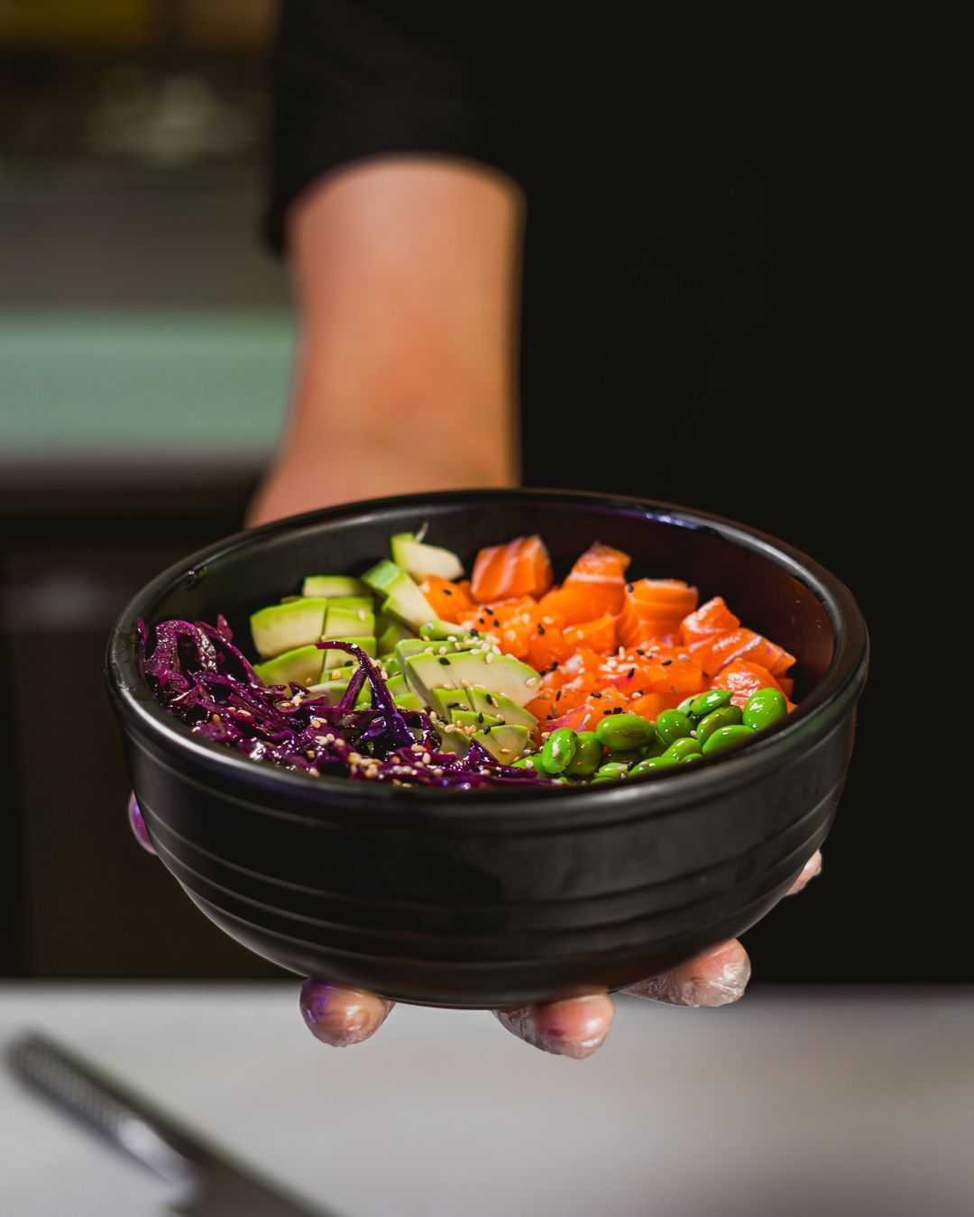 Bol de saumon frais accompagné de légumes croquants et de sésame, servi dans un restaurant japonais.