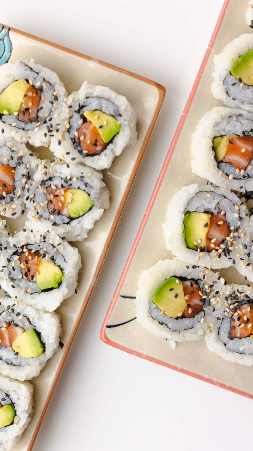 Sushi californien et maki avec avocat et saumon, présentés sur deux plateaux.