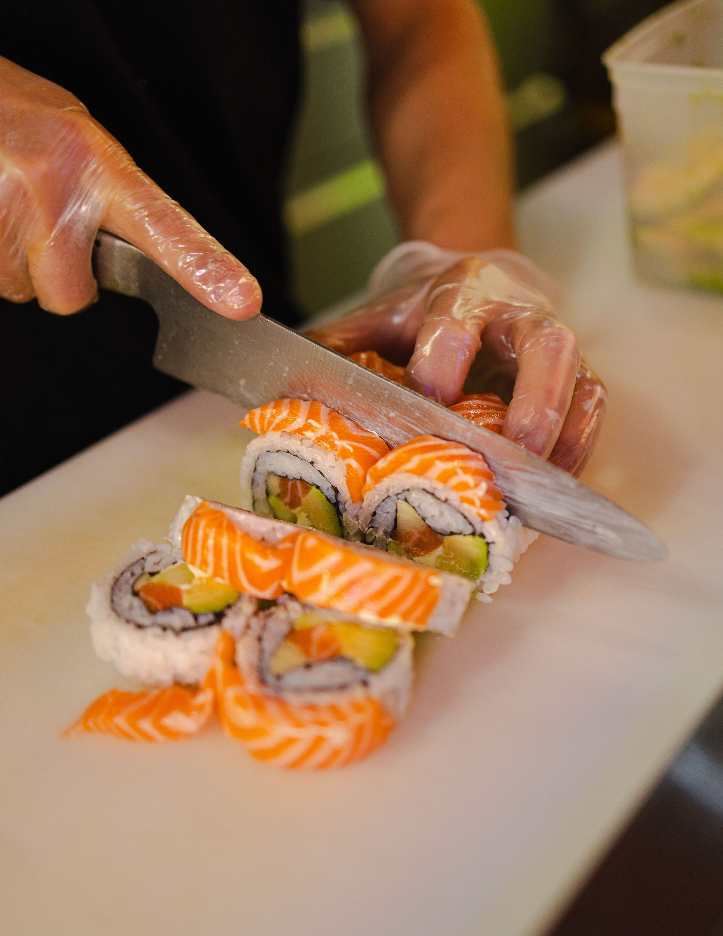 Découpe de rouleaux de sushi california avec saumon et avocat dans un restaurant japonais RollRoll.